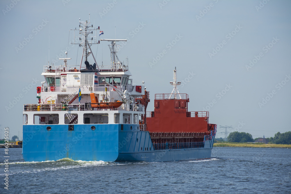 Blue cargo ship is sailing at the river.