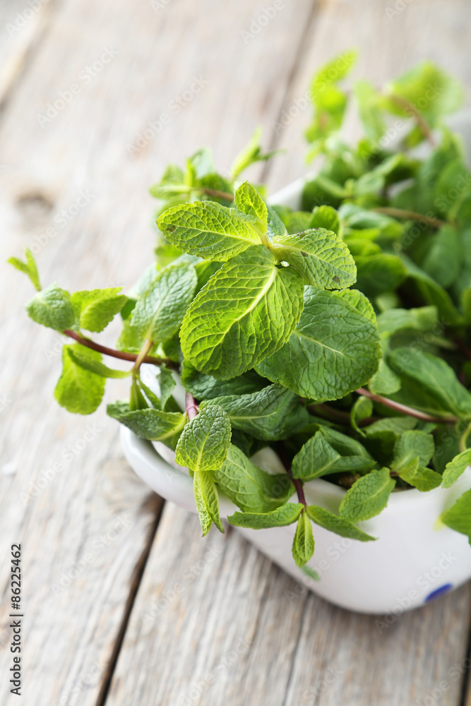 Fresh mint in bowl on grey wooden background Fresh mint in bowl on grey wooden background
