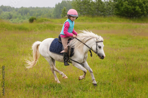 Young girl confident galloping horse on the field © andreipugach