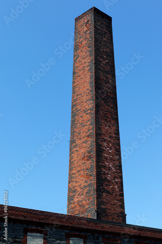 square old Industrial chimney made from red bricks against the b