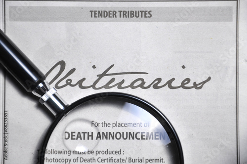 magnifying glass and obituaries advertisement on newspaper