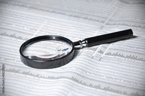 selective focus of magnifying glass and list of stock on newspap
