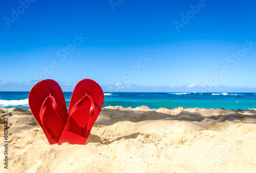 Red flip flops on the sandy beach