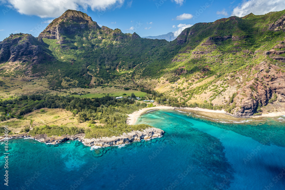 Aerial view of Kauai from a doors off Helicopter tour with lush green mountains and deep blue sea and a secluded beach