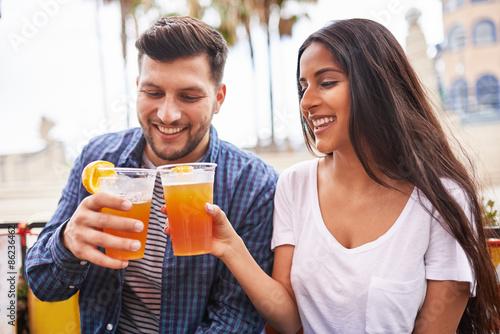 latin couple making drinking beer and making a toast in outdoor pub