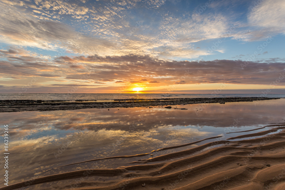 Obraz premium reflection of a beautiful sunrise in a calm tide pool protected by the reef on the Island of Kauai, Hawaii.