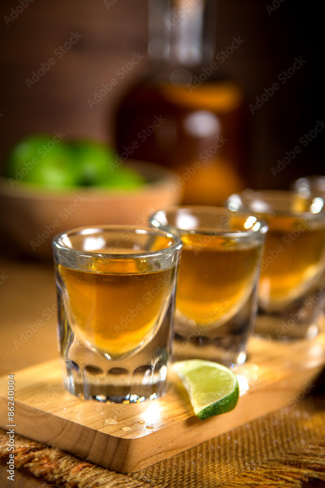 Close up of gold Tequila shots flight with cut limes and salt Close up of gold Tequila shots flight with cut limes and salt