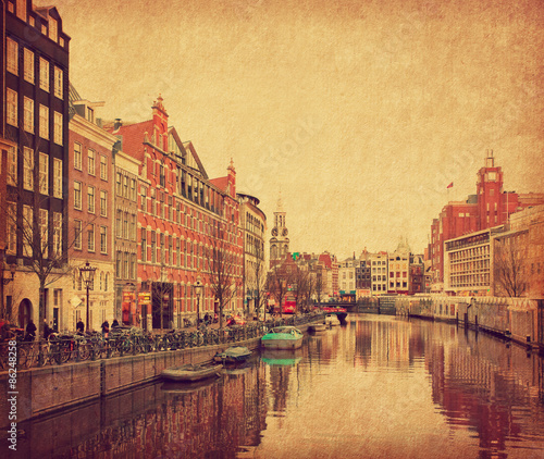 The Singel is one of the numerous canals in Amsterdam, Netherlands . In the background Munttoren . Photo in retro style. Paper texture. photo