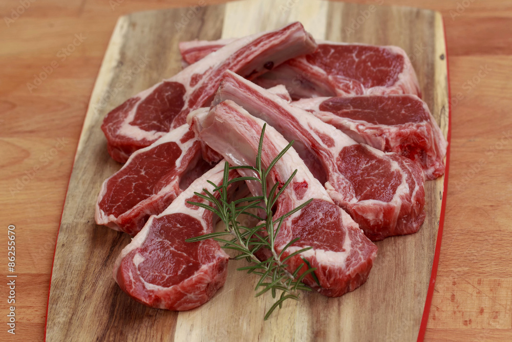 Raw lamb cutlets with rosemary on chopping board