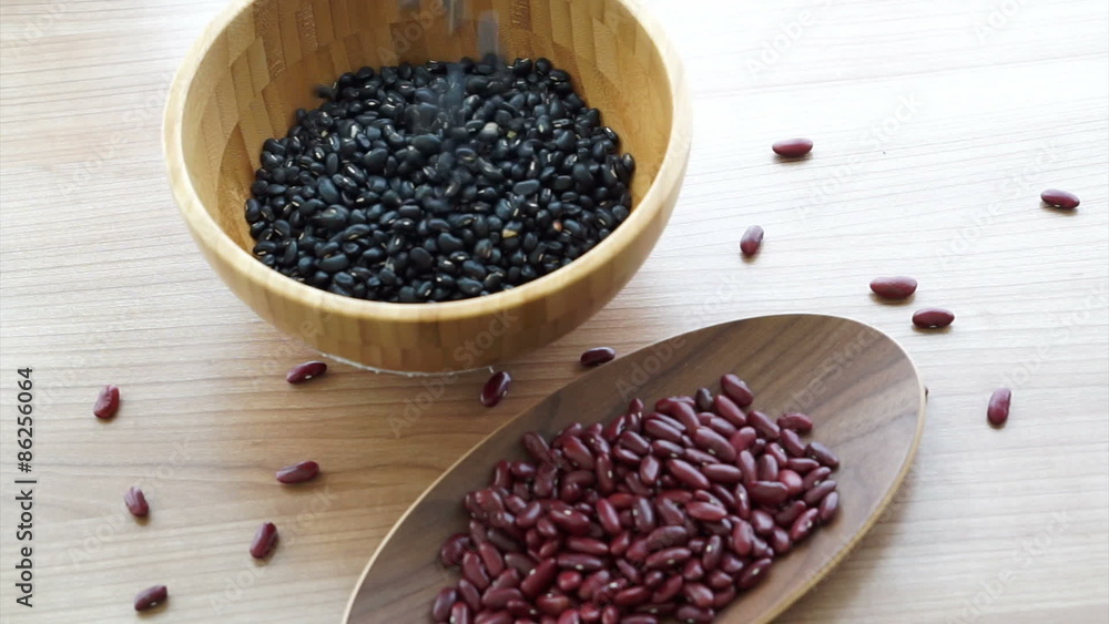 red and black beans pouring to fill wooden bowl red and black beans pouring to fill wooden bowl