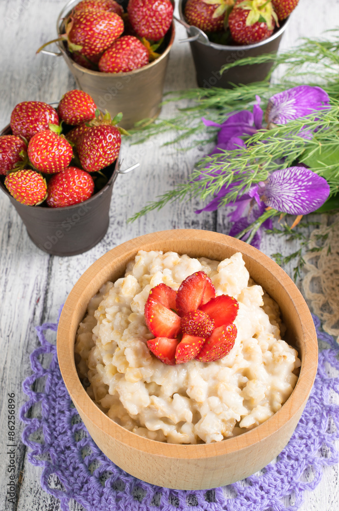 Oatmeal with strawberries in the wooden bowl Oatmeal with strawberries in the wooden bowl