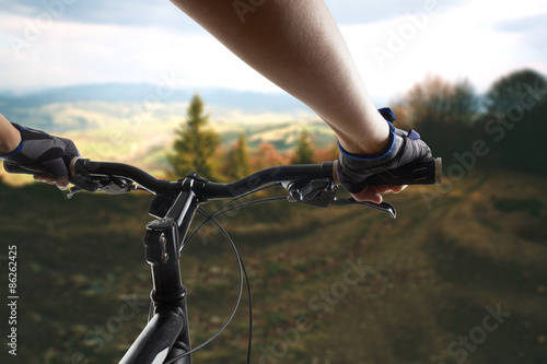 Hands in gloves holding handlebar of a bicycle. Mountain Bike cyclist riding single track. Healthy lifestyle active athlete doing sport