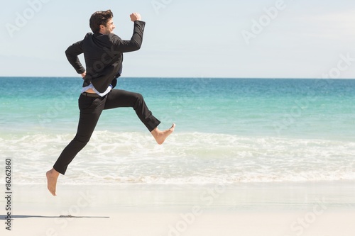 Businessman jumping in front of the sea 