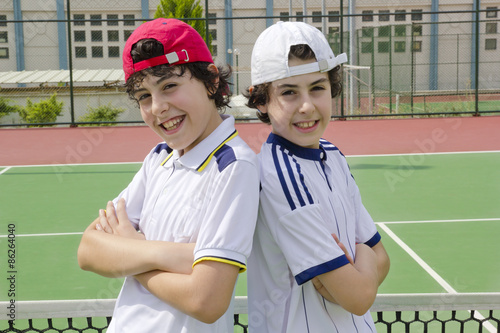 The twins are looking to the camera in the tennis court photo