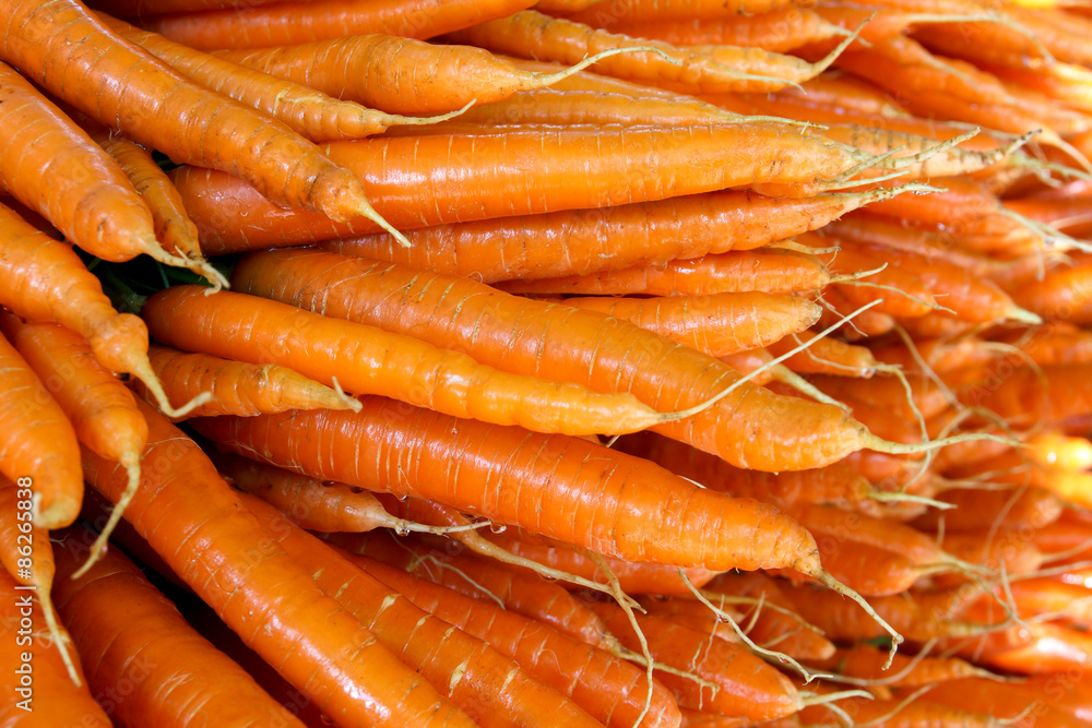 Many carrots arranged in a large stack at a farmers market. Many carrots arranged in a large stack at a farmers market.