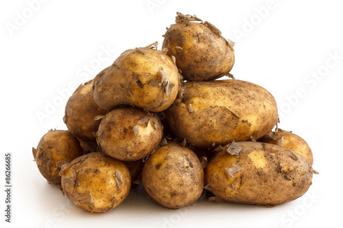 Pyramid heap of unwashed new potatoes isolated on white.