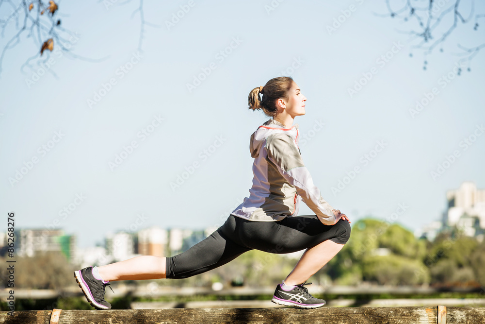 Young fit girl stretching out on bench before exercising in Young fit girl stretching out on bench before exercising in
