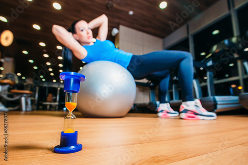 girl working out at gym with a ball, in the foreground of an ho