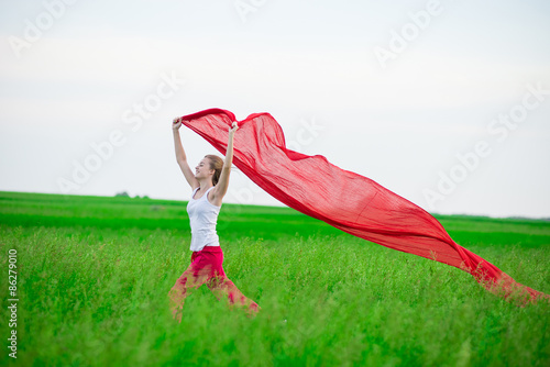 Young lady runing with tissue in green field. Woman and red