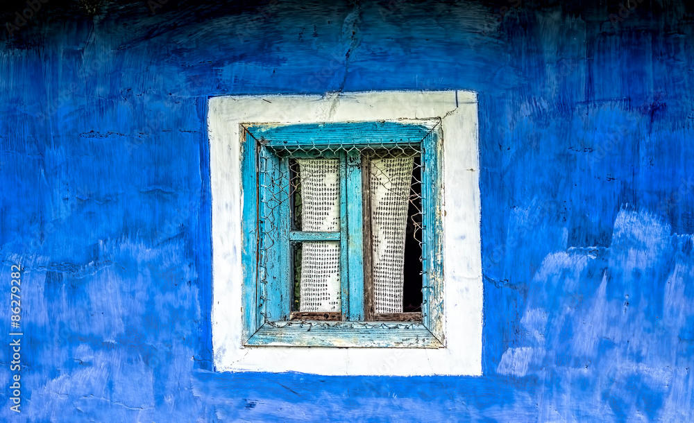 Old window with cyan wooden frame and crocheted curtain on a blue plastered hand painted wall. Old window with cyan wooden frame and crocheted curtain on a blue plastered hand painted wall.