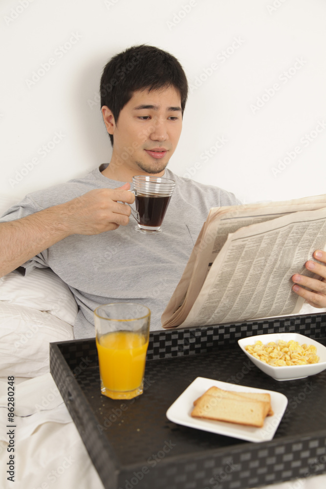 Man having a breakfast while reading the newspaper Man having a breakfast while reading the newspaper