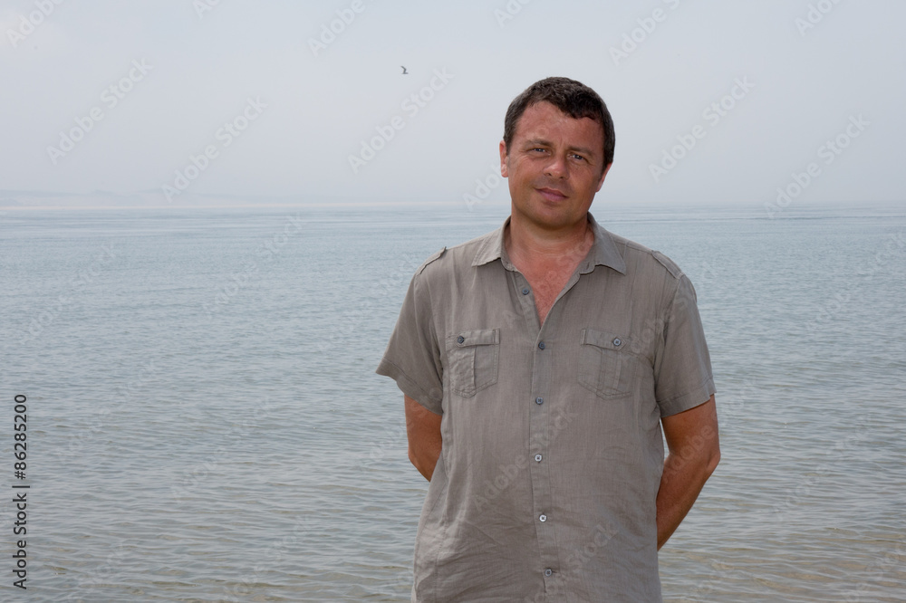 A very charming man at the beach looking at the camera