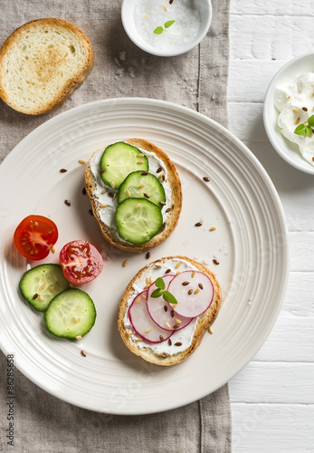healthy snack - sandwiches with cream cheese, cucumber and radishes on light plate