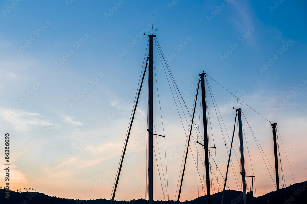 Silhouette of an one-masted touring boat in a harbor at sunset
