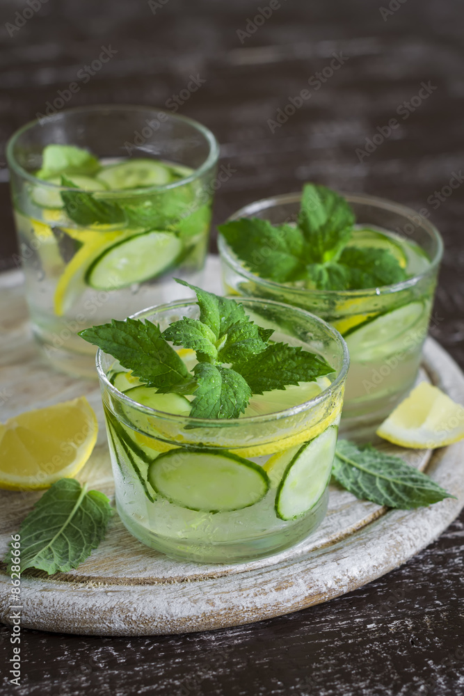 Lemonade with cucumber, lemon, mint and ginger in glass cups on a wooden surface Lemonade with cucumber, lemon, mint and ginger in glass cups on a wooden surface