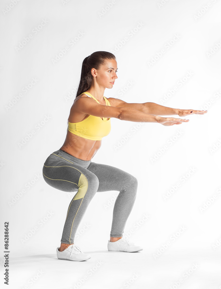 Fotografie Hispanic woman doing squats on white background