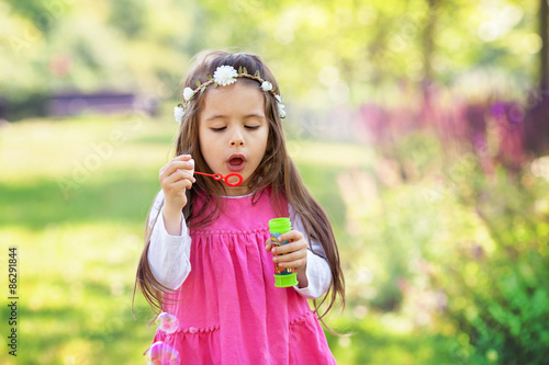 Beautiful portrait of sweet lovely little girl blowing soap bubb © Tomsickova