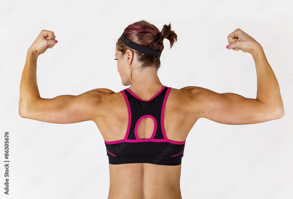 Beautiful strong muscular woman flexing her biceps and arm muscles. View  from behind to show her ripped back and arms. Stock Photo