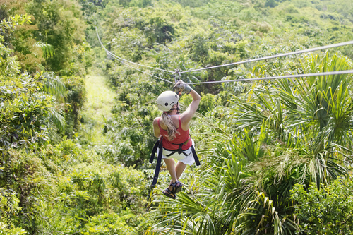 Woman going on a jungle zipline adventure. View from behind