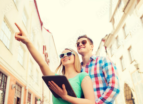 smiling couple with tablet pc in city