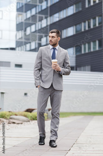 young serious businessman with paper cup outdoors © Syda Productions