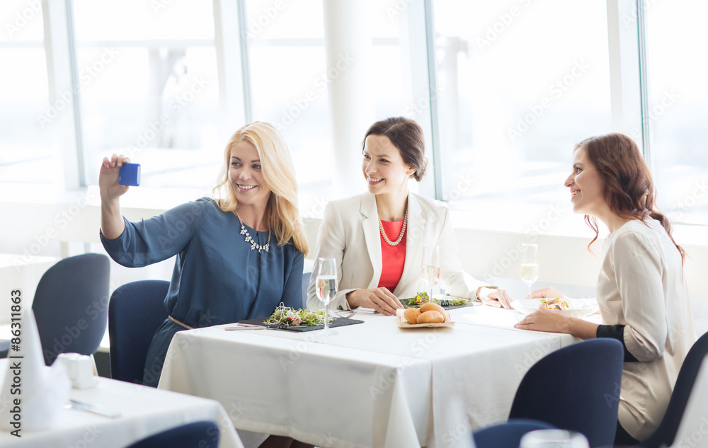 women with smartphone taking selfie at restaurant