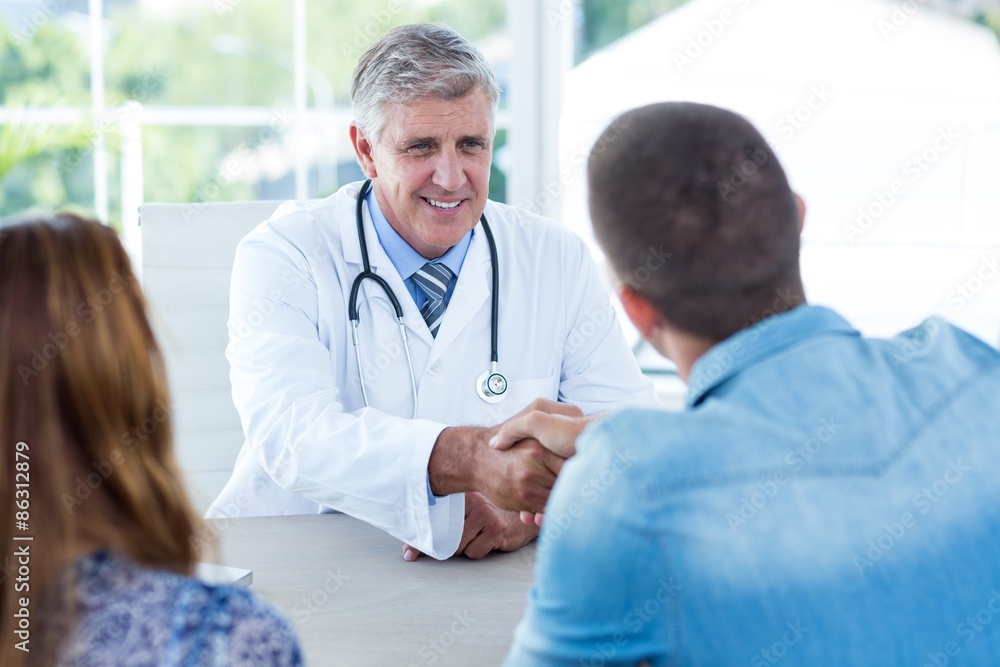 Fototapeta premium Smiling doctor greeting happy couple