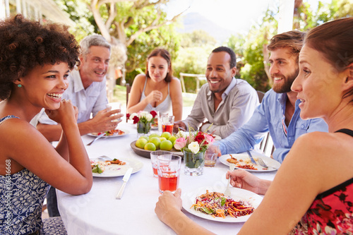 Friends dining together at a table in a garden photo