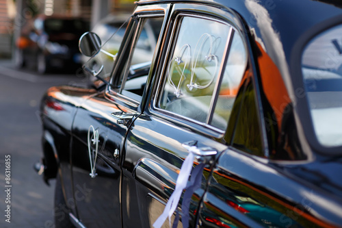 black vintage wedding car decorated with white bows © Irina Schmidt