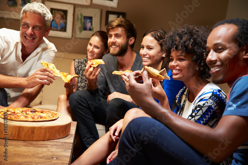 Friends eating pizza at a house party, watching television