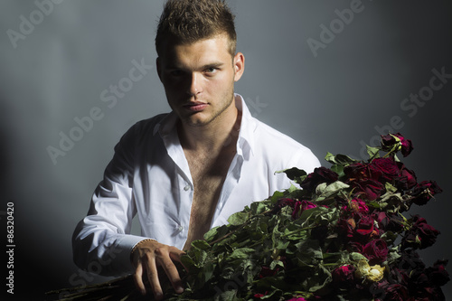 Portrait of handsome man with flowers in studio