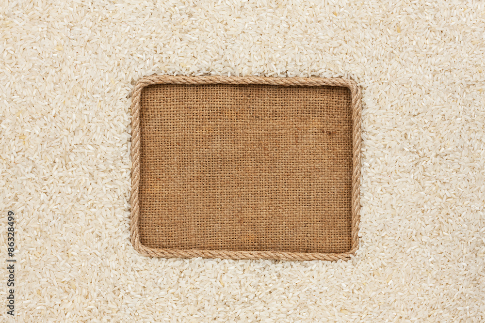 Fototapeta premium Frame made of rope with rice grains on sackcloth