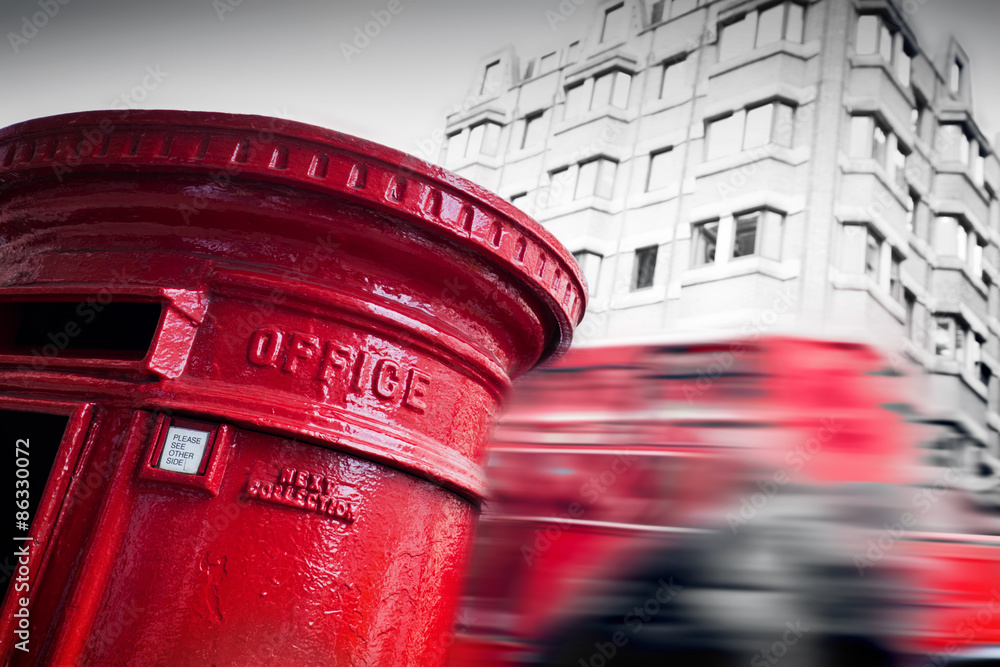 Fototapeta premium Traditional red mail letter box and red bus in motion in London, the UK.