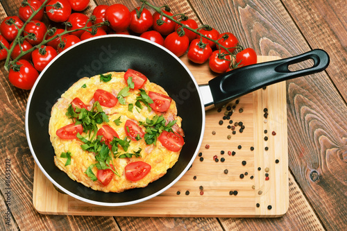 Omelette with ham, tomatoes and chees on the frying pan.