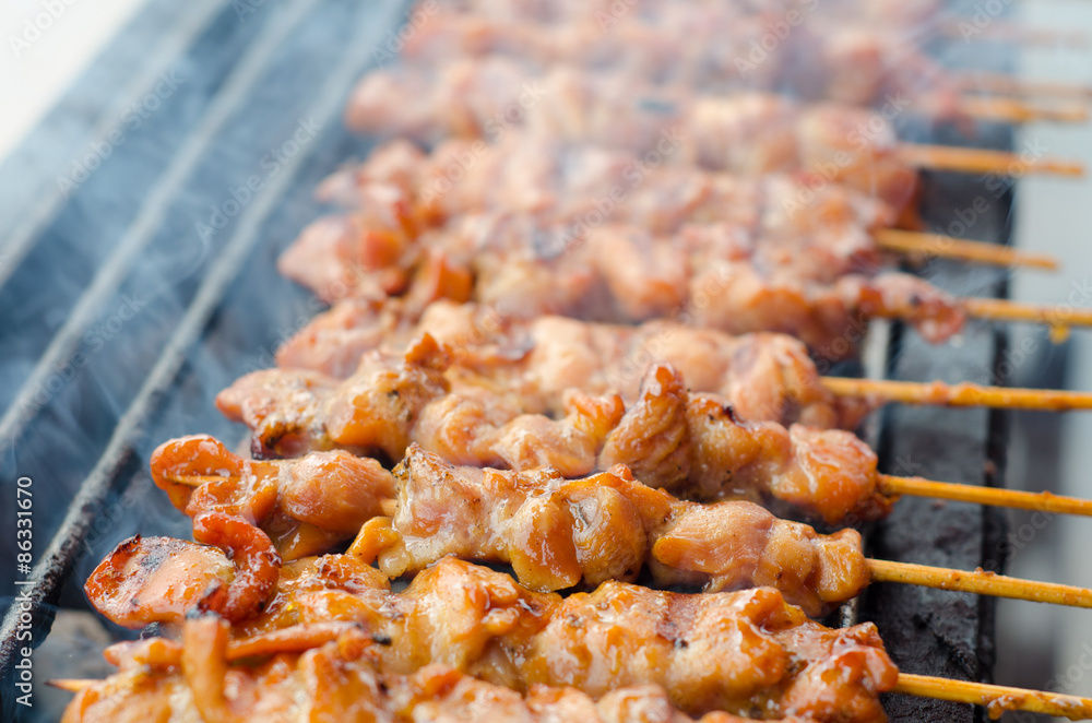 Skewer chicken pieces roasting on the grill and smoke