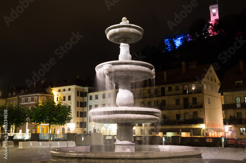 Ljubljana, Slovenia - June 23, 2015. Fountain in Novi trg (city square) at night on the background of Ljubljana castle.