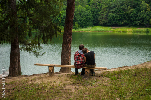 Couple sitting on a bench and looking at the lake