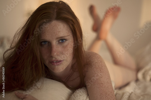 Fototapeta redhead in a bedroom at Sunset