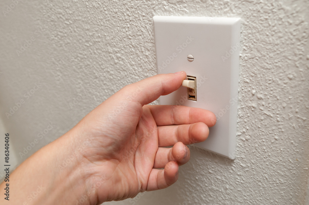 Hand turning wall light switch off. color image in horizontal orientation Hand turning wall light switch off. color image in horizontal orientation