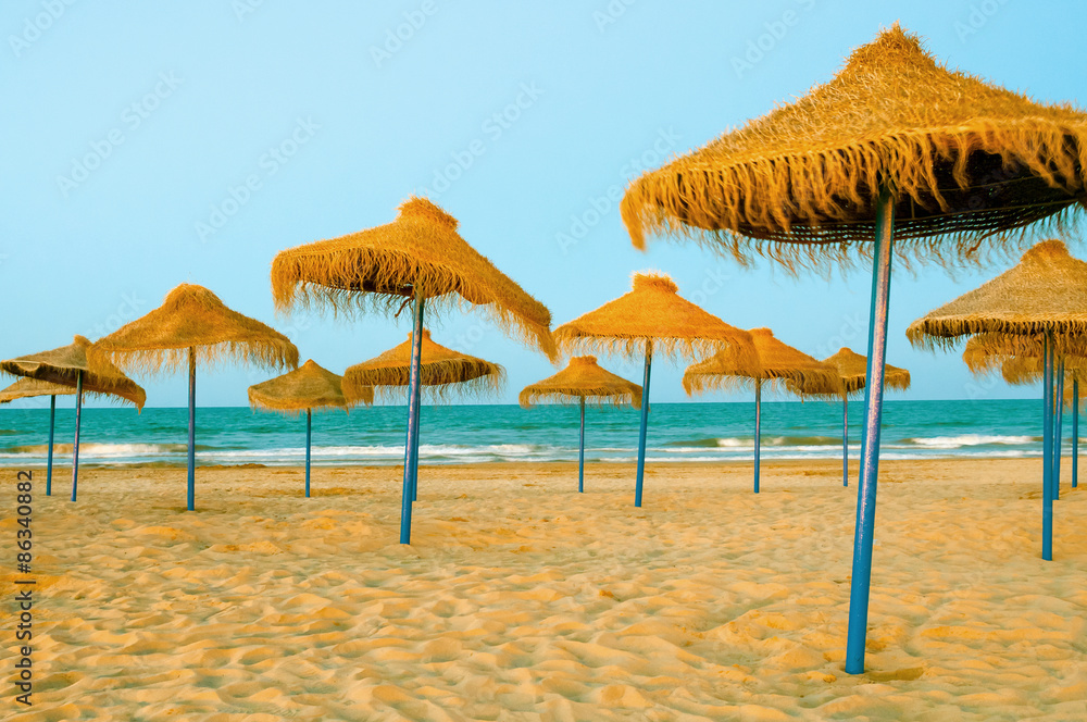 Reed umbrellas on the beach at evening